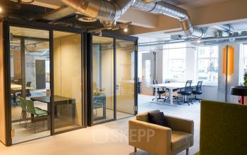 Modern office space rental at Weesperplein 4b in Amsterdam Center with glass-walled meeting rooms and furnished work areas.