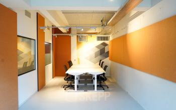 Interior view of a furnished workspace at Weesperplein 4b in Amsterdam Center, featuring modern seating options and white tables available for rent office space.