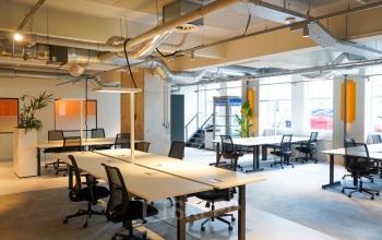 Spacious, modern office space for rent at Weesperplein 4b, Amsterdam Center, featuring long tables, natural light, and industrial design elements.