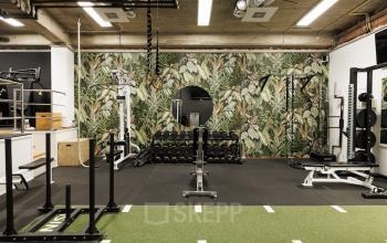 Office gym area at Herengracht 471, Amsterdam Center featuring workout equipment and a tropical-themed wall, ideal for those seeking office space rental with fitness facilities.