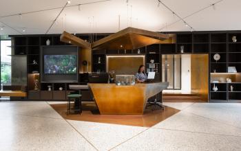 A modern office reception area at Herengracht 471, Amsterdam Center, featuring a stylish desk and a person working on a laptop. Ideal for office space rental.