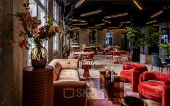 Trendy office lounge at Stationsplein 9, Amsterdam Center, featuring modern seating, plants, and stylish decor ideal for office space rental.
