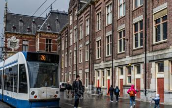 Exterior view of the office building located at Stationsplein 9, Amsterdam Center, Amsterdam with a tram passing by.