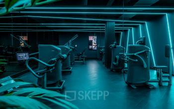 Modern gym area with various workout machines and glowing neon lights in a stylish design in the office building at Stationsplein 9, Amsterdam Center.