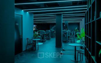 Modern furnished office space with sleek design, ambient lighting, plants, and exercise equipment at Stationsplein 9, Amsterdam Center. Ideal for office space rental.