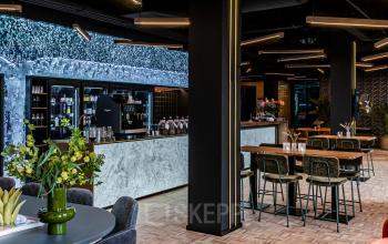 Spacious office cafeteria with modern decor at Stationsplein 9, Amsterdam Center, available for office space rental. Features contemporary seating, tables, and areas for coffee and refreshments.
