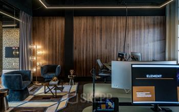 Office located at Stationsplein 9 in Amsterdam Center featuring modern workspaces with computers, stylish lighting, and comfortable seating area.