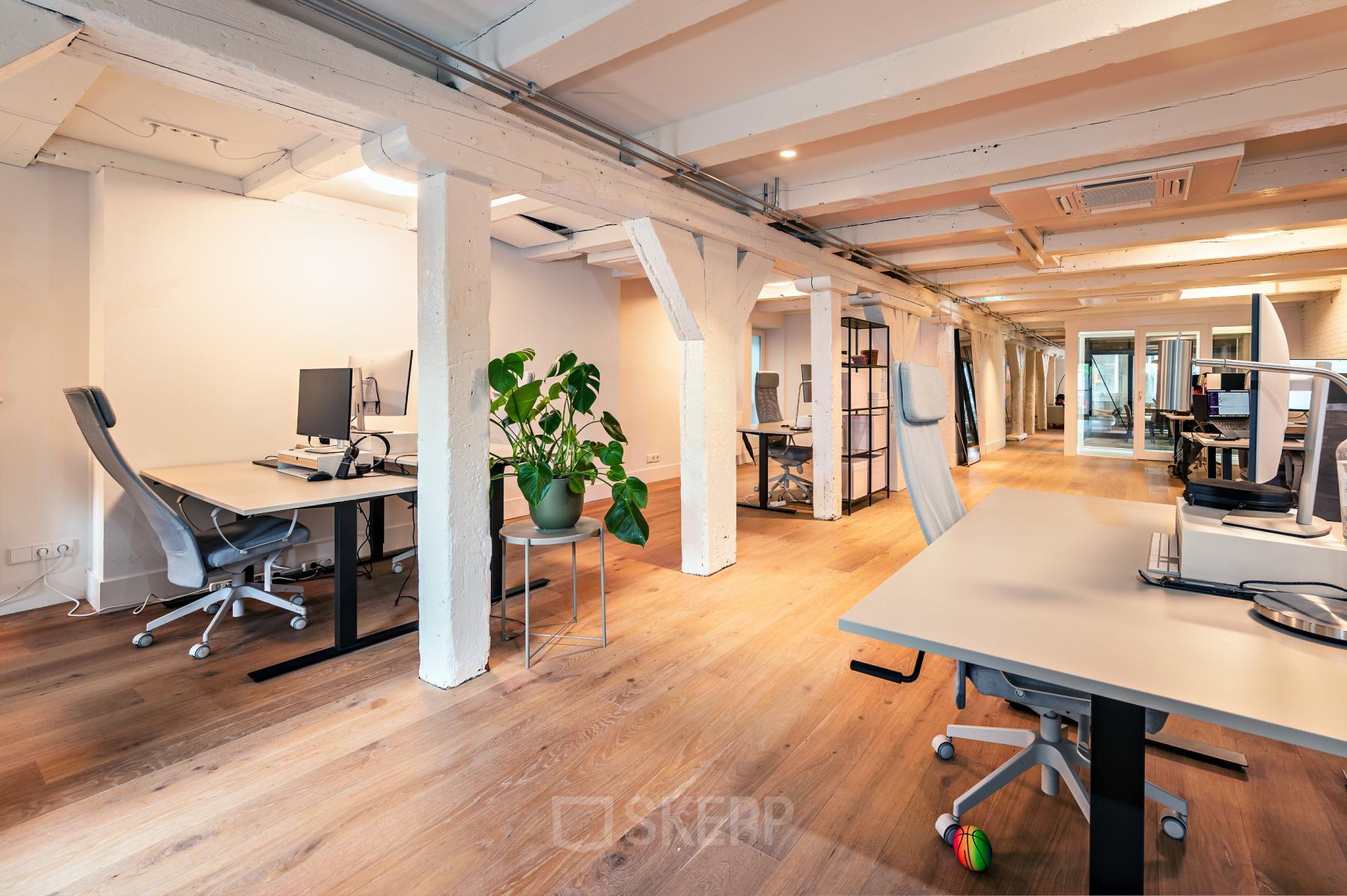 Bright open-plan office space rental at Brouwersgracht 167, Amsterdam Center, featuring wooden floors, modern desks, and exposed beams.