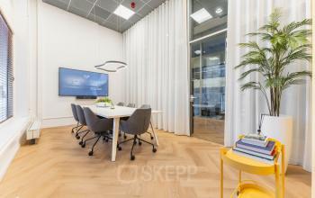 Bright conference room at Weesperstraat 107-121, Amsterdam Center, featuring a large screen, modern chairs, and a stylish decor, ideal for office space rental discussions.