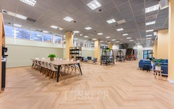 Spacious office to rent in Amsterdam Center featuring modern workspaces with wooden floors, ample seating, and natural light. Ideal for collaborative work and meetings at Weesperstraat 107-121.