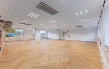 Spacious open-floor office space for rent at Weesperstraat 107-121, Amsterdam Center, featuring large windows and wooden flooring, ideal for customizable workspace setups.