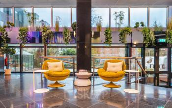 Stylish office lounge at Weesperstraat 107-121, Amsterdam Center, featuring modern seating and lush greenery, ideal for office space rental.