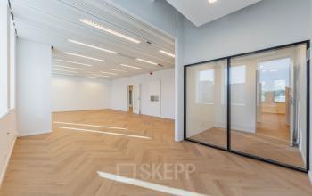 Bright office space with wooden floors and large windows at Weesperstraat 107-121, Amsterdam Center. Ideal for office space rental, featuring modern design and ample natural light.