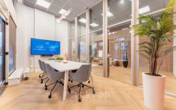 Modern conference room at Weesperstraat 107-121, Amsterdam Center, featuring a sleek table, comfortable chairs, and a large TV screen, perfect for productive meetings in office space rental.