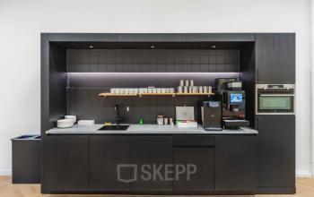 Minimalist black kitchenette with coffee machine and sink in modern Amsterdam office to rent at Weesperstraat 107-121.