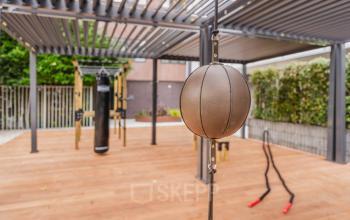 Outdoor gym area with wooden flooring, boxing equipment, and metal pergola at Weesperstraat 107-121, Amsterdam Center.
