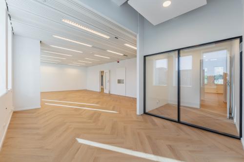 Modern unfurnished workspace at Weesperstraat 107-121 in Amsterdam Center, featuring sleek wooden floors and ample natural light, suitable for office space rental.