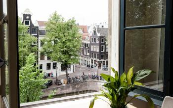 Bright office space at Keizersgracht 241, Amsterdam Center with canal view, large windows, and a table with a plant.