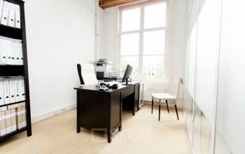 Office space for rent at Keizersgracht 241 in Amsterdam Center featuring a desk, chair, computer, and shelves with files.