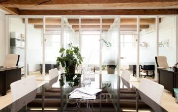 Modern office space at Keizersgracht 241, Amsterdam Center, featuring glass dividers, wooden beams, and a sleek conference table for a professional setting. Ideal for office space rental.