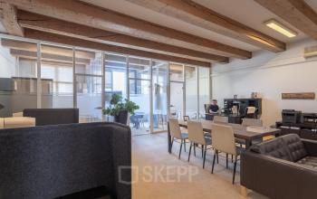 Bright and contemporary office space rental at Keizersgracht 241-2, Amsterdam Canal Belt, with a person working at a desk.