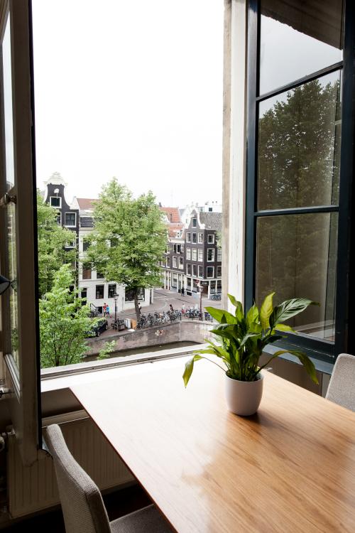 Bright office space at Keizersgracht 241, Amsterdam Center with canal view, large windows, and a table with a plant.
