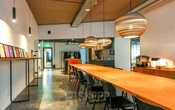Modern office space at Prins Hendrikkade 48 A in Amsterdam Center, featuring a long wooden table, stylish pendant lighting, and functional design, ideal for office space rental.
