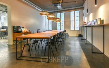 Spacious, modern office with long wooden table and pendant lights, ideal for collaborative meetings. Located at Prins Hendrikkade 48 A in Amsterdam Center, perfect for those seeking office space rental.