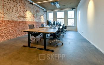 Spacious Amsterdam office at Prins Hendrikkade 48 A featuring exposed brick walls and large windows, ideal for teams seeking office space rental.