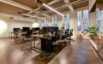 Modern workspace with sleek desks and ergonomic chairs in Amsterdam Center, featuring ample natural light. Ideal for office space rental, this setting encourages productivity and collaboration.