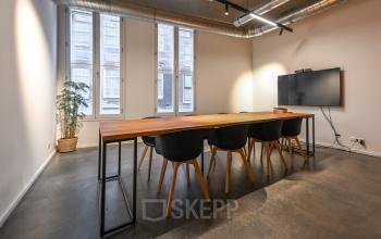 Interior office space at Prins Hendrikkade 48 A, Amsterdam Center, featuring a large conference table, modern chairs, and a wall-mounted TV, perfect for meetings and presentations in this office space rental.