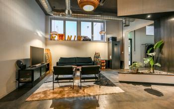 Modern, furnished lounge area at Prins Hendrikkade 48 A in Amsterdam Center, ideal for office space rental, featuring stylish seating, industrial ceiling design, and ample natural light.