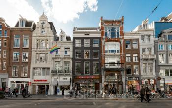 Exterior view of the office building at Rokin 46-1, Amsterdam Center. A vibrant street scene with bicycles and pedestrians passing by the mixed-use buildings showcasing a diverse architectural style.