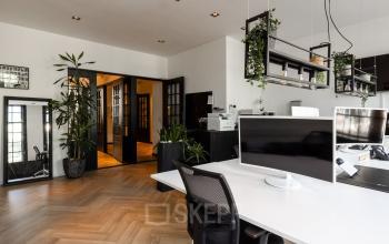 Modern office space at Rokin 46-1, Amsterdam Center, featuring sleek desks, large monitors, and greenery. Ideal for office space rental with contemporary design and vibrant city atmosphere.