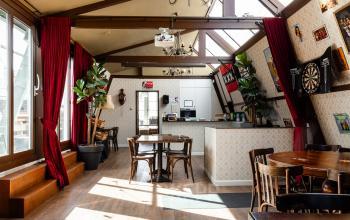 Bright and stylish office space at Rokin 46-1, Amsterdam Center, featuring wooden décor, a dartboard, and tables. Ideal for casual meetings or relaxed work sessions, available for office space rental.