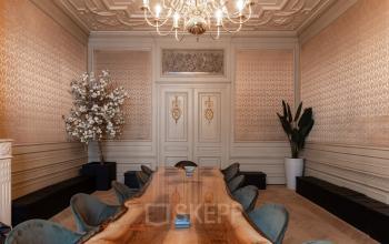 Elegant conference room with a long wooden table, plush chairs, and a chandelier at Rokin 46-1, Amsterdam Center. Ideal for office space rental.