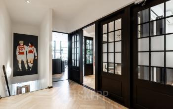 Interior view of Rokin 46-1, Amsterdam Center, featuring stylish wooden floors and dark-framed glass doors. Bright and spacious atmosphere ideal for dynamic office space rental.