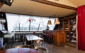 Charming workspace at Rokin 46-1, Amsterdam Center, featuring a cozy bar setup with wooden tables and seating, ideal for casual meetings or breaks. Perfect for those considering office space rental in a vibrant area.