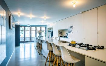 Spacious and modern pantry area at Groenmarktkade 5-H in Amsterdam Center, featuring a long counter with stylish bar stools and natural light from large windows. Ideal for office space rental.