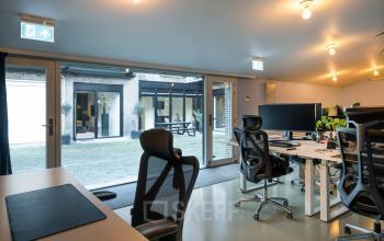 Modern office space rental at Groenmarktkade 5-H in Amsterdam Center, featuring sleek workstations with ergonomic chairs and large windows facing a courtyard.