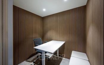Interior office space at Groenmarktkade 5-H, Amsterdam Center, featuring a sleek white desk, ergonomic chair, and wooden panel walls, ideal for office space rental.