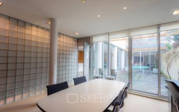 Modern conference room at Kerkstraat 204 in Amsterdam Center featuring a sleek table, stylish chairs, and large windows overlooking an outdoor area, ideal for office space rental.