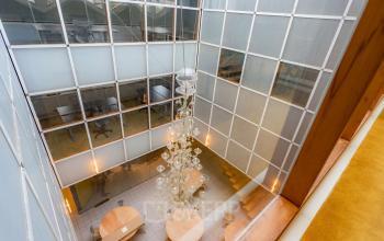 A modern, bright atrium with circular tables and a large chandelier, perfect for office space rental in Amsterdam Center.