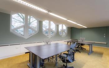 Bright office space with modern desks and ergonomic chairs, featuring unique geometric windows. Ideal for office space rental at Kerkstraat 204, Amsterdam Center.