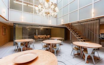 Office space rental at Kerkstraat 204 in Amsterdam Center features a modern open floorplan with natural light, wooden tables, and a stylish chandelier. Ideal for collaborative work settings.