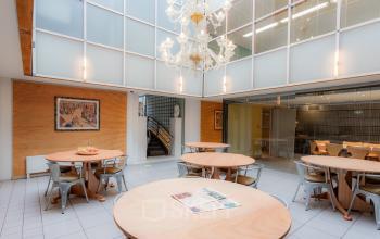 Spacious furnished office space for rent at Kerkstraat 204, Amsterdam Center, featuring round tables and a chandelier, ideal for collaborative work.