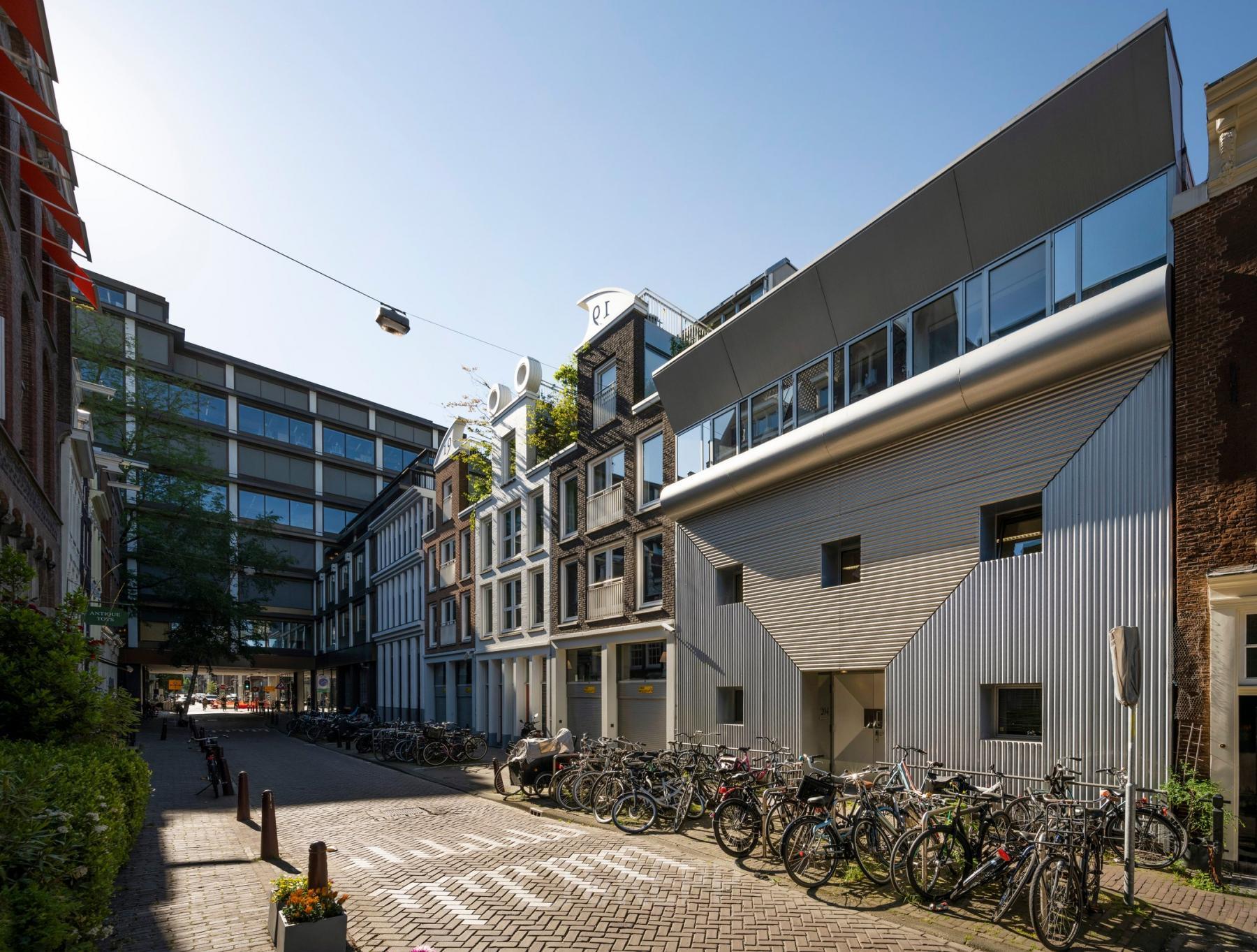 Exterior of the office building at Kerkstraat 204, Amsterdam Center, featuring modern architecture with large windows and surrounding bicycle parking. Ideal for those seeking office space rental in a vibrant location.