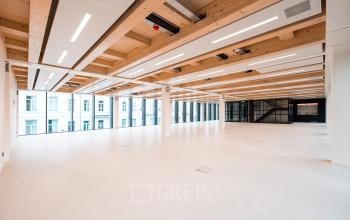 Spacious open floorplan office space with modern wooden ceiling beams and large windows in Pieter Cornelisz. Hooftstraat, Amsterdam Center, ideal for office space rental.