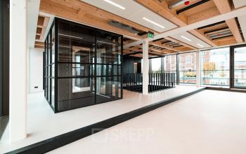 Modern, open office space rental at Pieter Cornelisz. Hooftstraat 7 7, Amsterdam. Features sleek design, large windows, and glass partitions for a bright, inviting workspace.