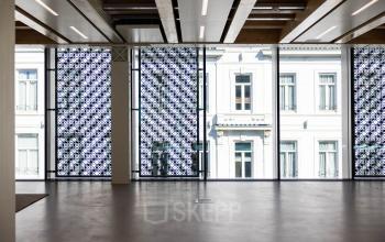 A bright office space with large windows and patterned screens, located at Pieter Cornelisz. Hooftstraat 7, in Amsterdam Center. Ideal for office space rental with natural light.